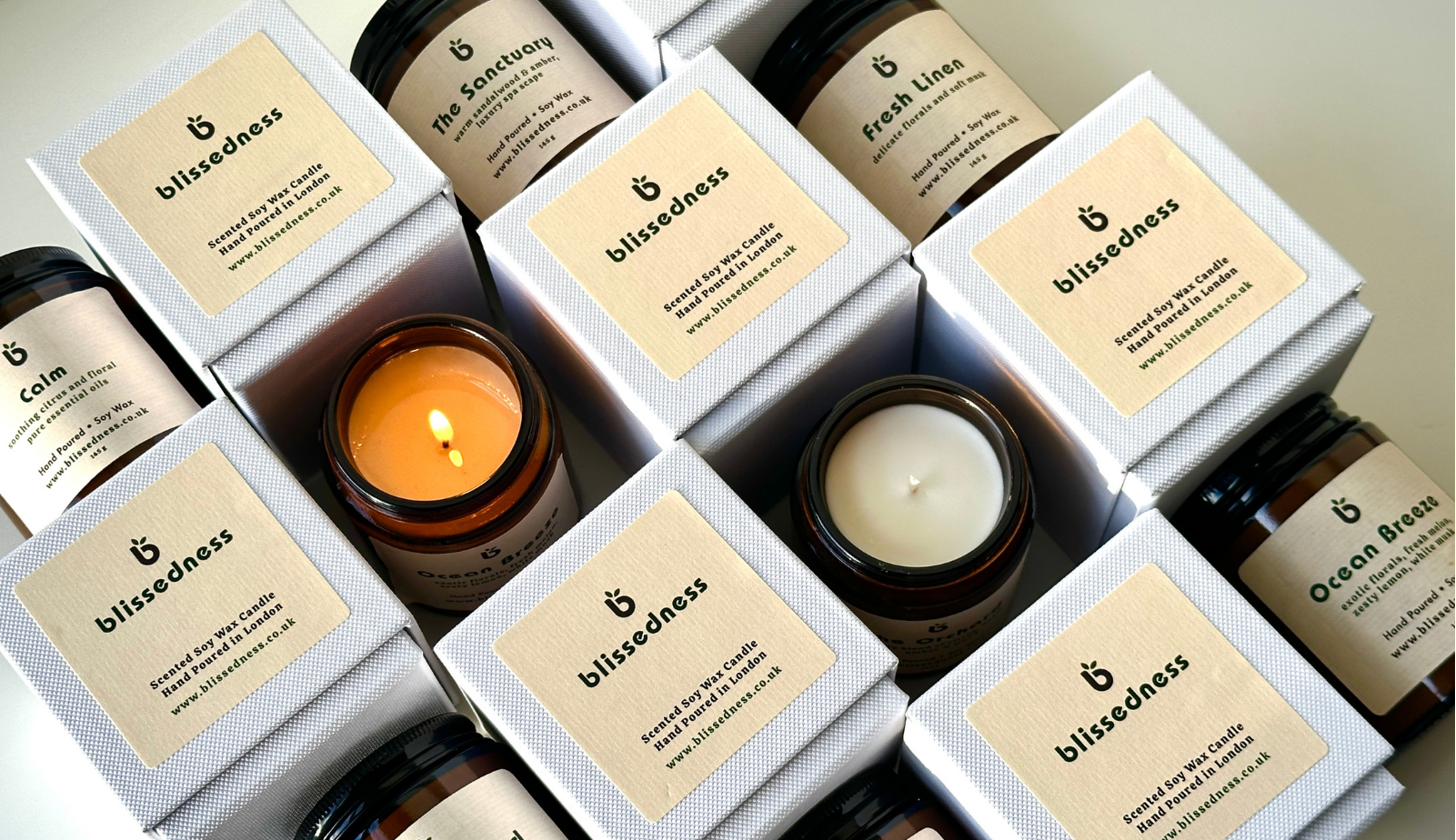 Blissedness soy candles in amber glass jars beside their branded gift boxes